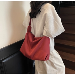 Close-up of a large capacity deep red canvas crossbody bag with adjustable wide strap