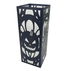 Close-up of black laser-cut Halloween candle cover with pumpkin and haunted house design