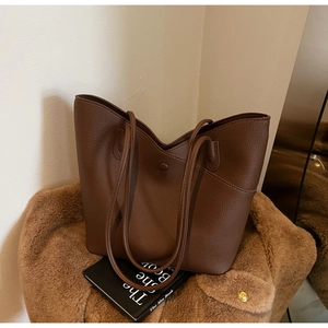 Close-up of brown litchi pattern leather tote bag on cozy coat with aesthetic vibes