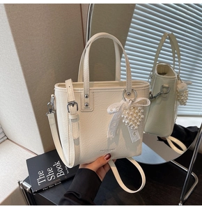 Détail du sac cabas crème en cuir plissé avec charm fraise perlée et nœud en soie