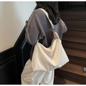 Detail of a large white slouchy tote bag showing soft matte texture and wide shoulder strap