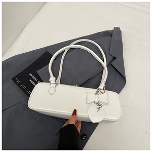Detailed view of white baguette bag with bow decor and heart charm on grey blazer