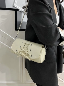 Chic cream white shoulder bag with lace-up bow design and silver metal eyelets