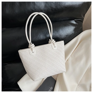 Detail of white woven tote bag showing herringbone texture and knotted shoulder strap