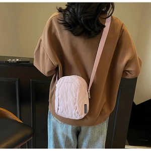 Détail du mini sac bandoulière lilas en nylon avec sangle réglable sur sweat marron
