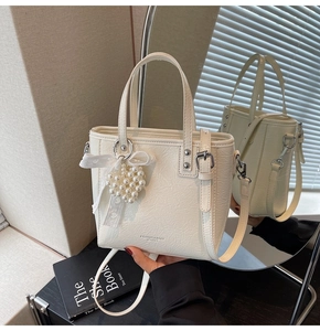 Détail du sac à bandoulière crème plissé avec breloque cœur perle et nœud en dentelle