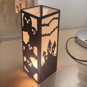Halloween paper lantern with laser-cut castle and ghost silhouettes in warm light