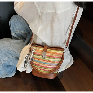 Detail of colorful woven bucket bag featuring brown leather trim and metallic lock closure