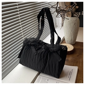 Detail view of black pleated nylon tote with decorative bows and textured fabric surface