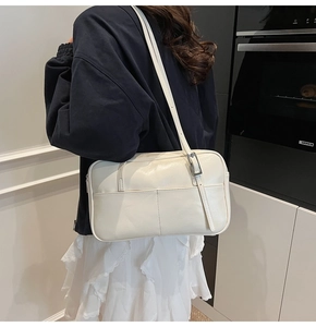 Detail van de minimalistische beige PU-leren schoudertas met verticale stiksels en zilveren gesp