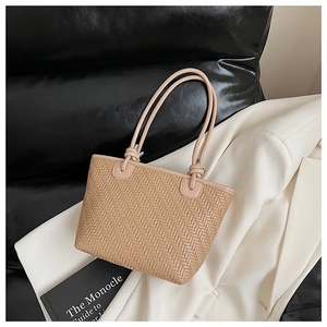 Close-up of khaki woven tote bag showing fine leather texture and knotted handle detail