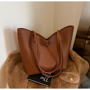 Detail of brown litchi pattern leather tote bag with secure snap closure and long straps