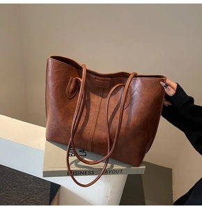 Detail of vintage brown leather texture and long straps on a large capacity tote bag