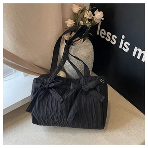 Detailed texture of black pleated nylon tote bag with decorative bow accents