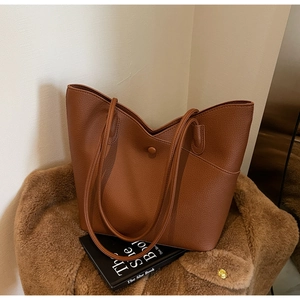 Detail of a brown lychee pattern tote bag with V-shaped opening on a fuzzy coat