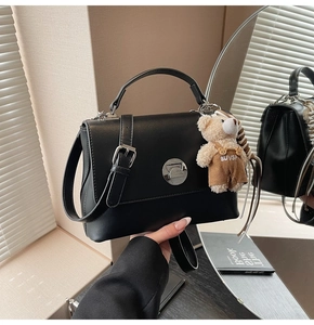 Detail of black vintage crossbody bag with silver buckle and cute bear pendant charm