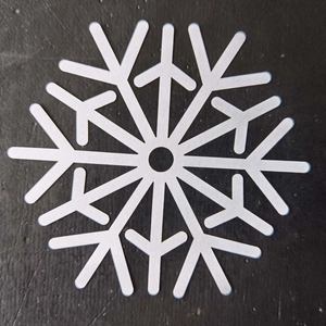 Close-up of laser-cut white snowflake coaster decoration on a black textured background