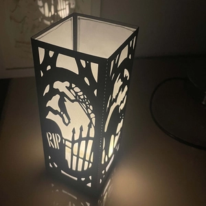 Macro shot of black Halloween lantern featuring RIP graveyard cutout and warm LED glow