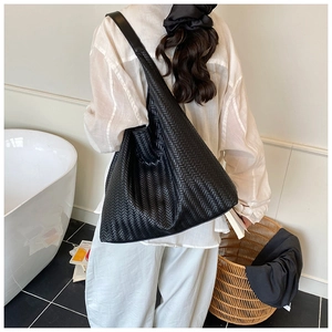 Rückansicht eines Models mit der schwarzen geflochtenen Hobo-Tasche in moderner Umgebung