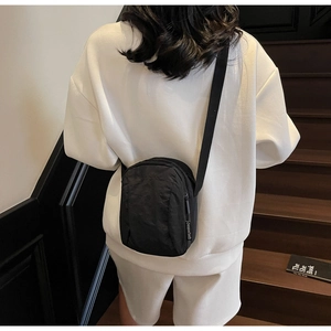 Vue arrière d'un mannequin portant une petite sacoche en nylon noir dans un escalier