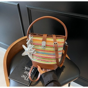 Detail of color-block woven bucket bag with leather handle and star charm on wooden chair
