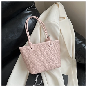 Detailed view of pink woven tote bag with knotted cord handle on white blazer background