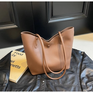 Detail of classic brown lychee texture leather tote with magnetic buckle and straps