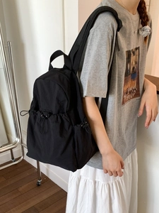 Lightweight black nylon backpack with side drawstring pockets for hiking and travel