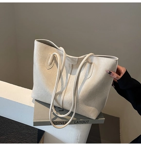 Detail of a large cream tote bag with distressed faux leather texture on white table