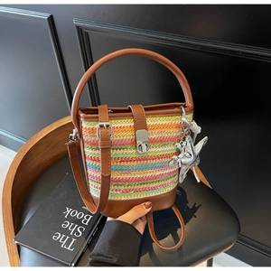 Detail of colorful woven bucket bag with brown leather trim and star pendant