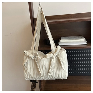 Detail of pleated oxford fabric and large decorative bows on a white tote shoulder bag