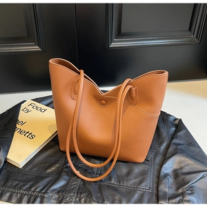 Detail of brown textured leather tote bag showing magnetic clasp and side pocket