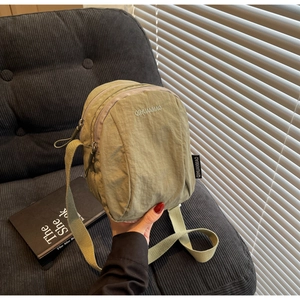 Gros plan du mini sac bandoulière en nylon vert olive avec double fermeture éclair