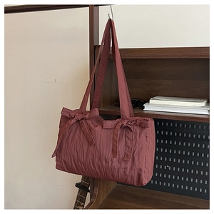 Detail view of pink pleated nylon bucket bag with cute bows on dark wooden background
