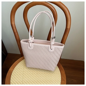 Close-up of pink woven tote bag showing detailed texture and silver buckle on a wooden chair