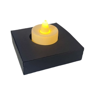 Dettaglio di lumino LED giallo caldo con base in carta nera traforata al laser