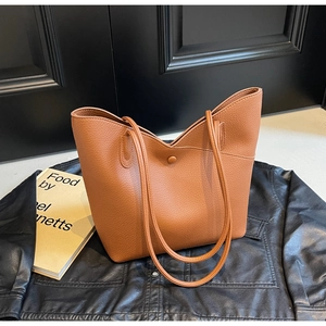 Close-up of caramel brown lychee pattern tote bag with shoulder straps on a leather jacket