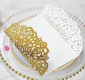 Détail du motif de rose dorée découpé au laser sur carte de mariage blanche sur plateau