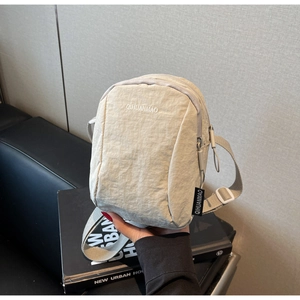 Détail de la sacoche bandoulière en nylon blanc cassé avec logo QIHUANMAO brodé