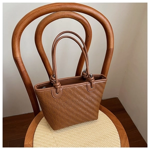 Detailed close-up of brown woven tote bag on a rustic chair showing craftsmanship