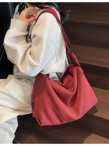 Large capacity red canvas crossbody tote bag worn by model in casual street style