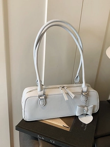 Elegant light blue leather baguette bag with bow and heart charm on a black book