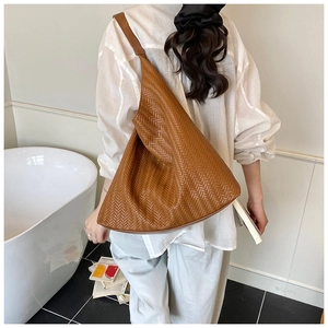Nahaufnahme der geflochtenen Ledertextur einer braunen Hobo-Tasche mit detailliertem V-Muster