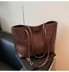 Close-up of retro brown tote bag showing textured PU leather and distressed matte finish