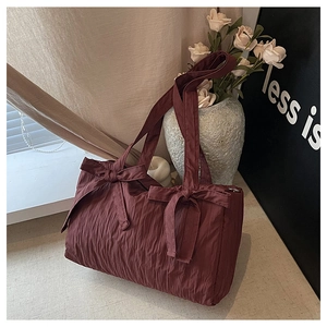 Detail of burgundy nylon bucket bag showing pleated texture and decorative bows