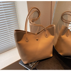 Detailed close-up of camel litchi grain leather tote bag with V-shaped top and snap button