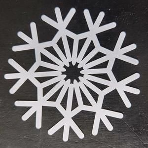 Macro shot of white snowflake paper coaster on black background for Christmas party