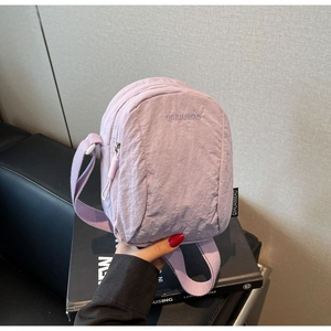 Détail d'un petit sac bandoulière en nylon violet clair avec doubles fermetures