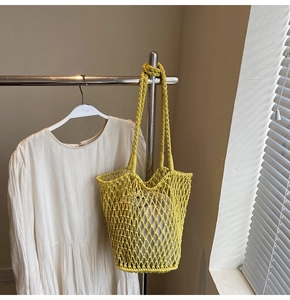 Detail of yellow knit hollow tote bag with a beige fabric liner and woven straps