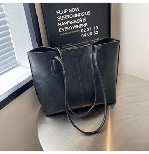 Close-up of black leather tote bag with subtle wrinkled texture on a metal table
